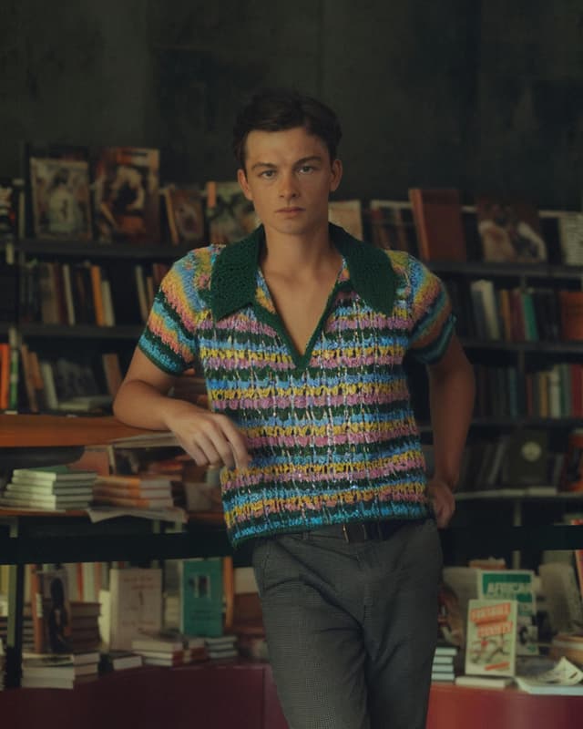Man in cotton polo, pants, in front of books